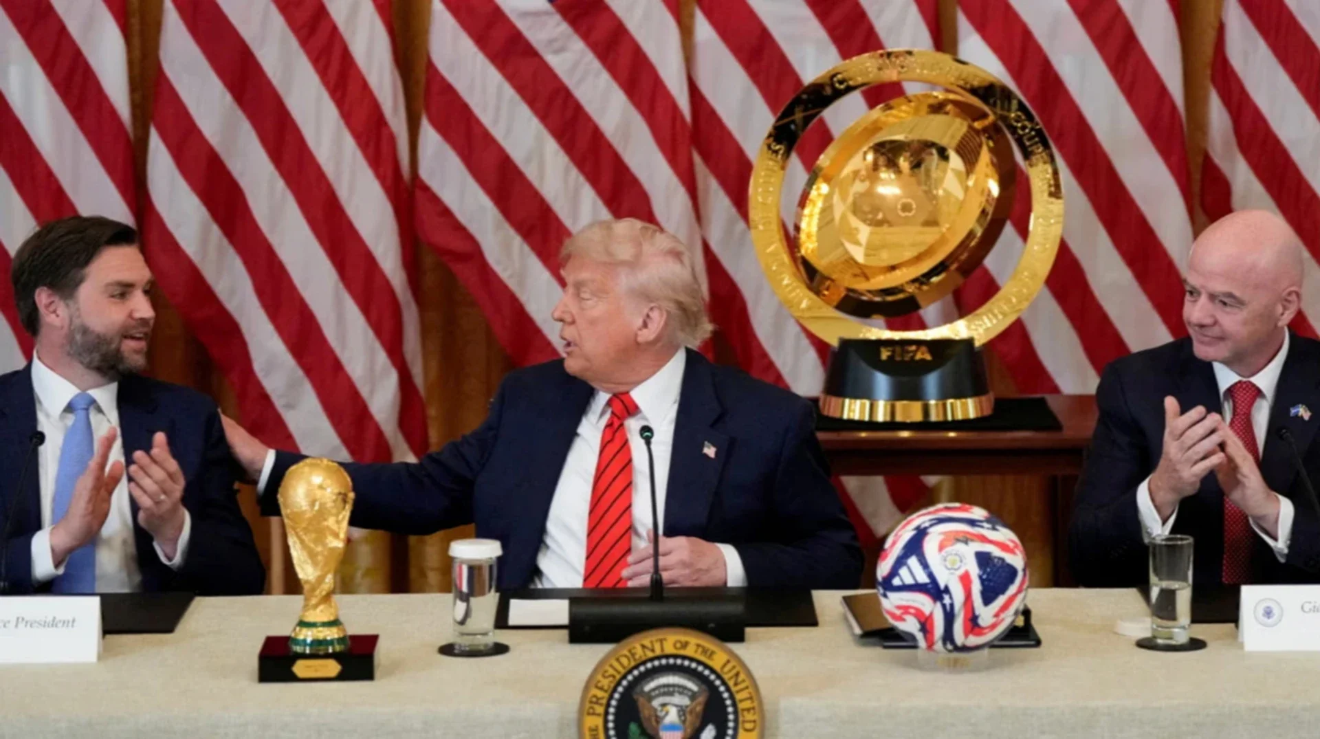 Дональд Трамп з кубком FIFA та мячем на тлі прапорів США