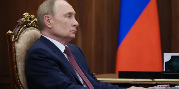 Владимир Путин в кресле на фоне флага России по поводу Донбасса