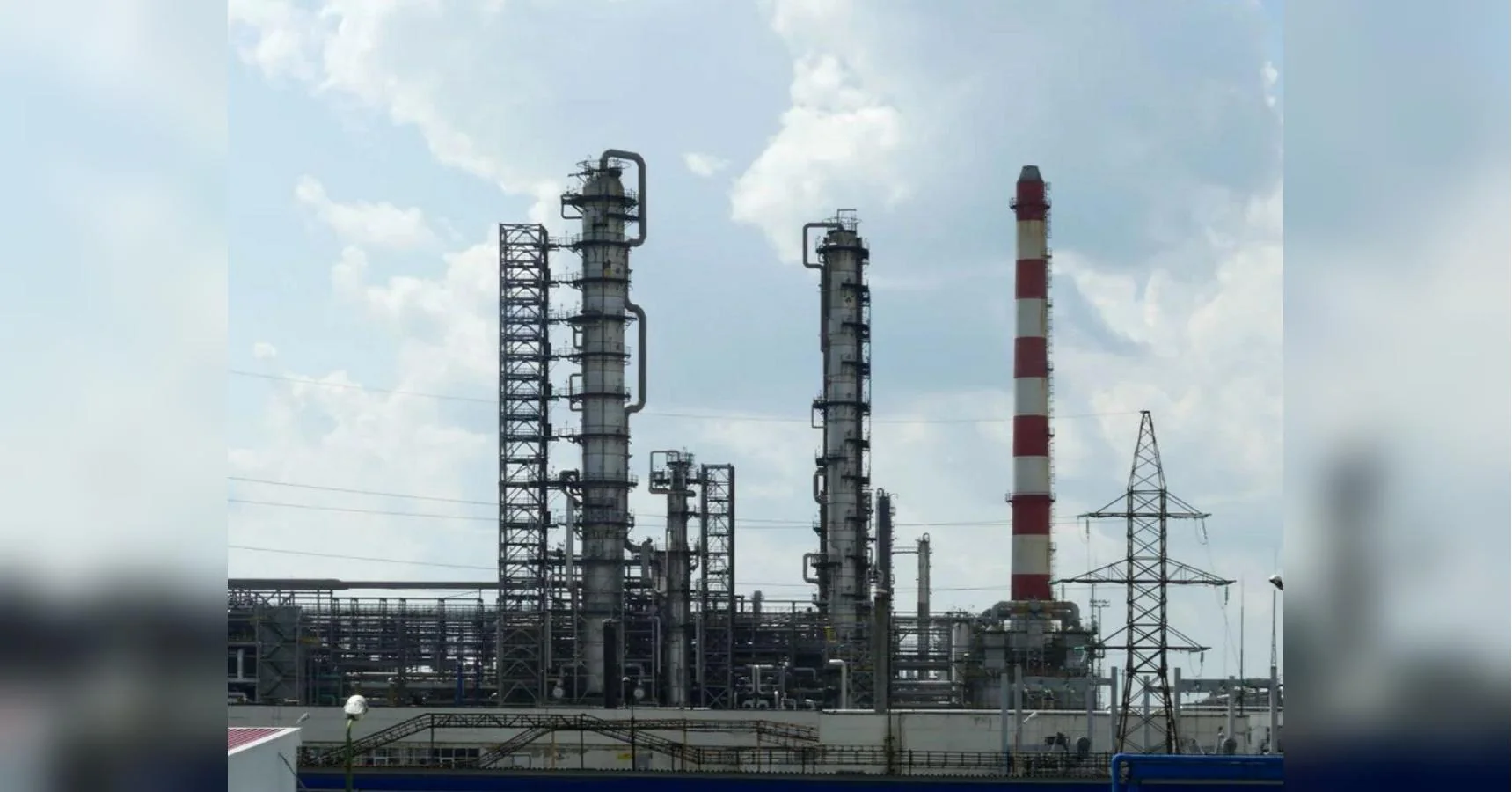 Високі колони та червоно-біла труба промислового нафтопереробного комплексу